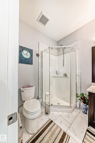 Corner glass-enclosed shower with white marble-look tile surround and a matching marble-look tile floor - 69 Caragana Way, Fort Saskatchewan, AB 
