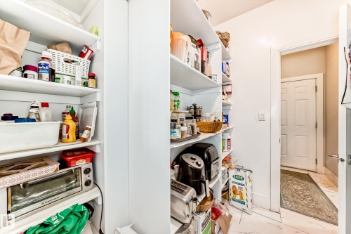 Bright pantry featuring extensive built-in shelving, white walls, and a light-toned flooring - 69 Caragana Way, Fort Saskatchewan, AB 