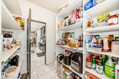 Walk-in pantry featuring extensive built-in shelving, white walls, and a white tile floor - 69 Caragana Way, Fort Saskatchewan, AB 