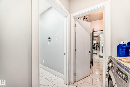 White door with modern horizontal paneling, brushed nickel hardware, and marble-finish tile flooring - 69 Caragana Way, Fort Saskatchewan, AB 