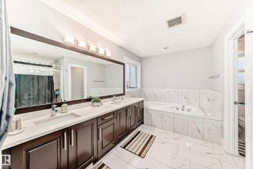 Bathroom featuring a dual-sink vanity with dark wood cabinetry and light-toned countertops - 69 Caragana Way, Fort Saskatchewan, AB 