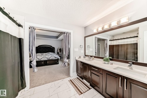 Double vanity with dark wood-finish cabinetry, white countertops, and modern chrome faucets - 69 Caragana Way, Fort Saskatchewan, AB 