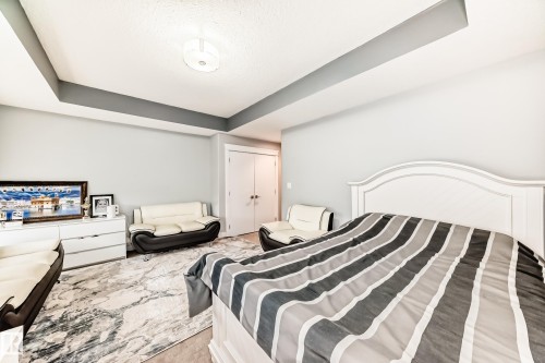 Spacious room featuring a tray ceiling with recessed lighting, light-toned wall paint, and double bi-fold doors - 69 Caragana Way, Fort Saskatchewan, AB 