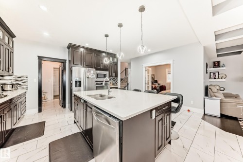 Kitchen featuring a large central island with a sink, white countertop, and pendant lighting - 69 Caragana Way, Fort Saskatchewan, AB 