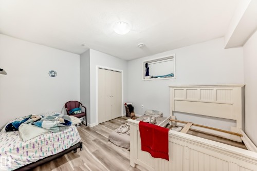Light gray walls with wood-finish flooring, featuring a flush-mount ceiling light and a small window - 69 Caragana Way, Fort Saskatchewan, AB 