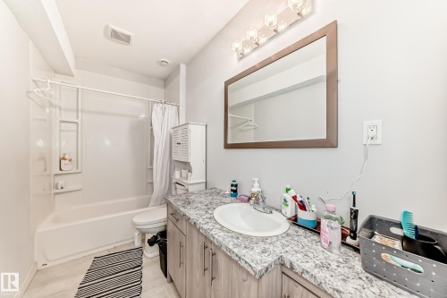 Bathroom featuring a vanity with a white oval sink, speckled countertop, and wood-finish cabinetry - 69 Caragana Way, Fort Saskatchewan, AB 