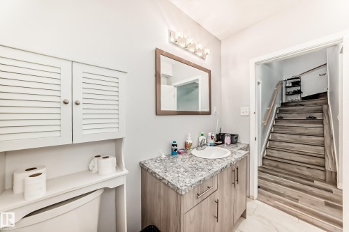 Bathroom featuring a light wood-finish vanity with a built-in sink and a granite-style countertop - 69 Caragana Way, Fort Saskatchewan, AB 
