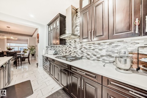 Contemporary kitchen featuring dark wood cabinetry, light countertops, and a patterned tile backsplash - 69 Caragana Way, Fort Saskatchewan, AB 