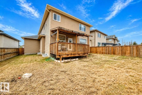Expansive backyard featuring a wood deck with a pergola, tan siding, and a wooden privacy fence - 69 Caragana Way, Fort Saskatchewan, AB 