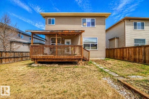 Spacious backyard featuring a multi-level wooden deck with a covered portion, offering direct access to the interior - 69 Caragana Way, Fort Saskatchewan, AB 