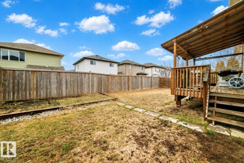 Expansive backyard featuring a covered wood deck, wood privacy fence, and concrete stepping stones - 69 Caragana Way, Fort Saskatchewan, AB 
