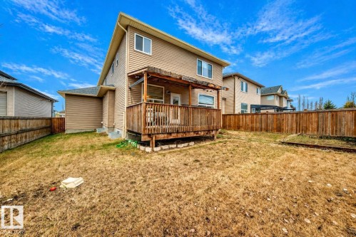 Expansive backyard featuring a large wooden deck with a pergola, fully fenced perimeter, and a two-story exterior with neutral siding - 69 Caragana Way, Fort Saskatchewan, AB 