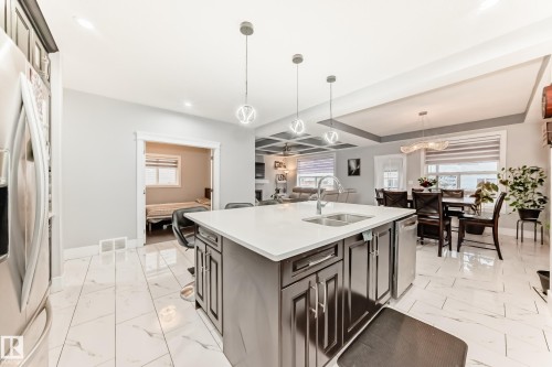Kitchen island featuring a double basin sink and integrated dishwasher - 69 Caragana Way, Fort Saskatchewan, AB 