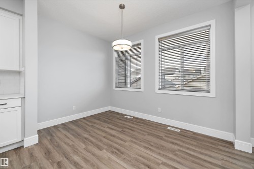 Open-concept room featuring wood-finish flooring, light gray walls, white baseboards, and two windows with blinds - 4235 Chichak Close, Edmonton, AB - Indoor Photo Showing Other Room