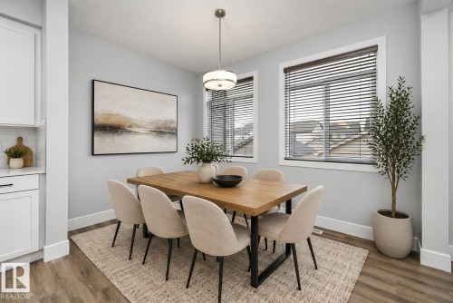 Dining area featuring wood-finish flooring, two large windows, a ceiling-mounted light fixture, and white baseboards - 4235 Chichak Close, Edmonton, AB - Indoor Photo Showing Dining Room