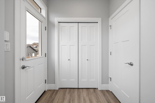 Entryway featuring plank-style flooring, a white front door with sidelight, and a pair of bifold closet doors - 4235 Chichak Close, Edmonton, AB - Indoor Photo Showing Other Room