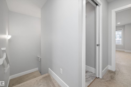 Carpeted staircase with white handrails and a wall-mounted light fixture - 4235 Chichak Close, Edmonton, AB - Indoor Photo Showing Other Room