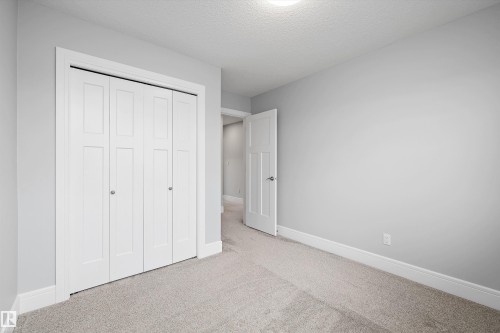 White bi-fold closet doors with brushed nickel knobs, light gray wall paint, white baseboards, and neutral-toned carpet - 4235 Chichak Close, Edmonton, AB - Indoor