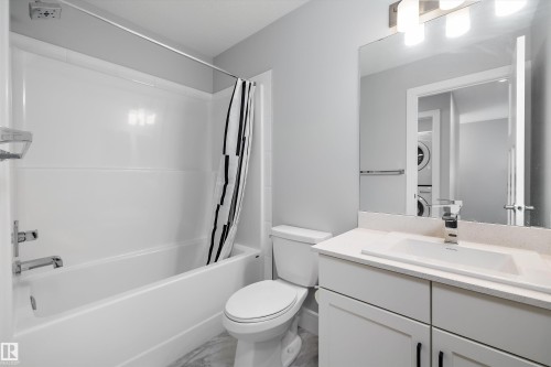Bathroom featuring a white tub and shower combination, a white vanity with an integrated sink, a light-colored countertop, and a vanity mirror with overhead lighting - 4235 Chichak Close, Edmonton, AB - Indoor Photo Showing Bathroom