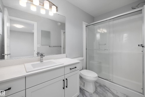 Contemporary bathroom featuring a spacious vanity with an undermount sink, a large wall-mounted mirror, and a modern light fixture - 4235 Chichak Close, Edmonton, AB - Indoor Photo Showing Bathroom