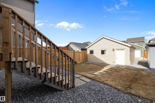 Detached garage featuring siding exterior, an outdoor wall sconce, and a side entry door - 4235 Chichak Close, Edmonton, AB - Outdoor