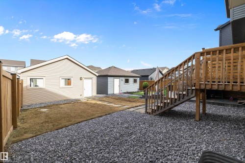Rear yard featuring a wood deck with stairs, a gravel ground cover, and a separate detached garage with siding - 4235 Chichak Close, Edmonton, AB - Outdoor