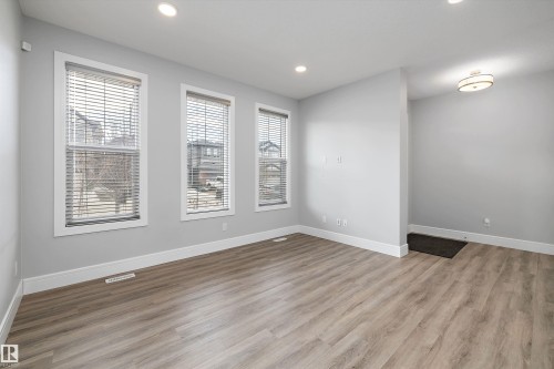 Open concept living area featuring wood-finish flooring, recessed lighting, and three large windows with blinds - 4235 Chichak Close, Edmonton, AB - Indoor Photo Showing Other Room
