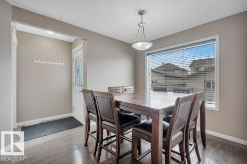 Dining area featuring wood-finish flooring, a large window with horizontal blinds, and a semi-flush mount light fixture - 12063 19 Avenue, Edmonton, AB - Indoor Photo Showing Dining Room