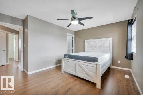 Spacious room featuring wood-finish flooring, a contemporary ceiling fan, and ample natural light from the window with blinds - 12063 19 Avenue, Edmonton, AB - Indoor Photo Showing Bedroom