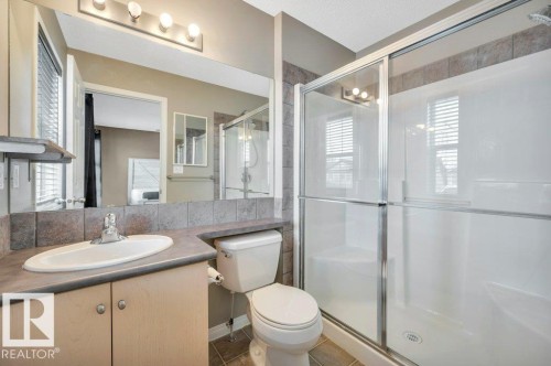 Bathroom featuring a wood-finish vanity with an integrated sink, a large wall-mounted mirror, and a tile backsplash - 12063 19 Avenue, Edmonton, AB - Indoor Photo Showing Bathroom