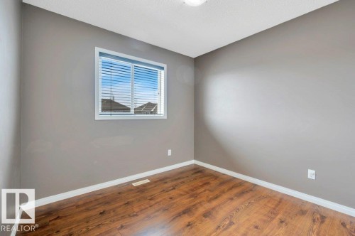 Room featuring wood-finish flooring, neutral gray walls, and white baseboards - 12063 19 Avenue, Edmonton, AB - Indoor Photo Showing Other Room