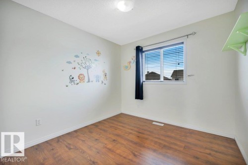 Room featuring wood-finish flooring, white baseboards, a single window with blinds, and a flush-mount ceiling light - 12063 19 Avenue, Edmonton, AB - Indoor Photo Showing Other Room
