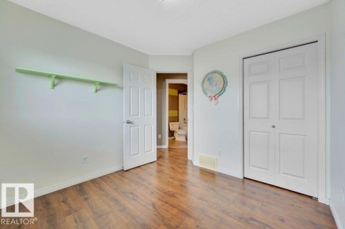 Room featuring wood-finish flooring, white baseboards, and a bi-fold closet door - 12063 19 Avenue, Edmonton, AB - Indoor Photo Showing Other Room