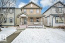 Two-story home with a covered front porch featuring white railing, light tan siding, and a decorative gable detail - 12063 19 Avenue, Edmonton, AB  - Outdoor With Deck Patio Veranda With Facade 