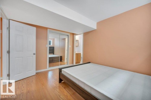 Room featuring wood-finish flooring, a white panel door, and mirrored closet doors - 12063 19 Avenue, Edmonton, AB - Indoor Photo Showing Other Room