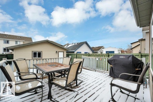 Wood deck with white railing, featuring an exterior door and a window on the adjacent building - 12063 19 Avenue, Edmonton, AB - Outdoor With Deck Patio Veranda With Exterior