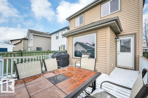 Ground-level wood deck featuring a white railing and exterior door with a decorative glass insert - 12063 19 Avenue, Edmonton, AB - Outdoor With Deck Patio Veranda With Exterior