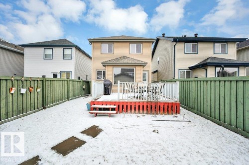 Rear exterior featuring a two-story residence with beige siding and dark trim - 12063 19 Avenue, Edmonton, AB - Outdoor With Deck Patio Veranda With Exterior