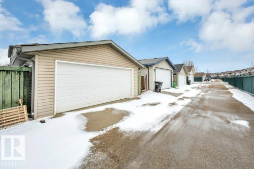 Rear detached garage with light beige siding and a white overhead door - 12063 19 Avenue, Edmonton, AB - Outdoor