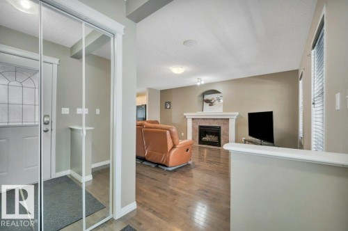 Hardwood-finish flooring extending from the entryway into the living area - 12063 19 Avenue, Edmonton, AB - Indoor With Fireplace
