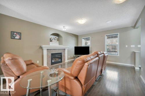 Living space featuring wood-finish flooring and neutral wall tones - 12063 19 Avenue, Edmonton, AB - Indoor Photo Showing Living Room With Fireplace