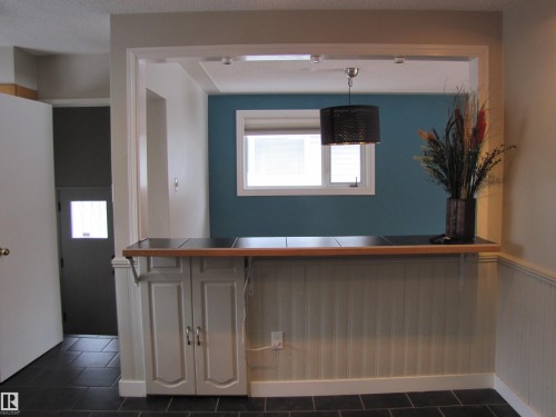 Kitchen pass-through with wood-finish countertop and dark tile surface - 7135 87 Street, Edmonton, AB - Indoor Photo Showing Other Room