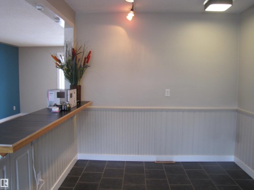 Interior space featuring dark tile flooring, wainscoting, and a built-in counter with a wood-finish edge - 7135 87 Street, Edmonton, AB - Indoor