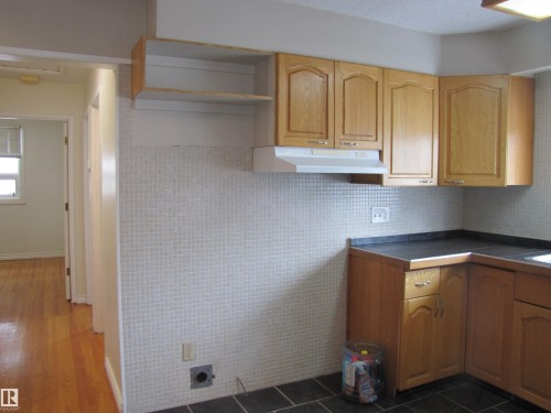 Kitchen featuring wood-finish cabinetry, dark countertops, and a white tile backsplash - 7135 87 Street, Edmonton, AB - Indoor Photo Showing Kitchen