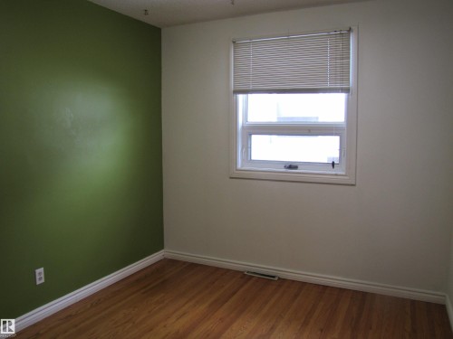 Room featuring wood-finish flooring, a white window frame, and a contrasting accent wall - 7135 87 Street, Edmonton, AB - Indoor Photo Showing Other Room