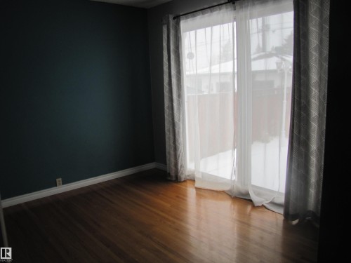 Wood-finish flooring with white baseboards - 7135 87 Street, Edmonton, AB - Indoor Photo Showing Other Room