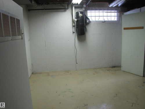 Utility room featuring painted concrete walls, a window with security bars, and a central vacuum system - 7135 87 Street, Edmonton, AB - Indoor