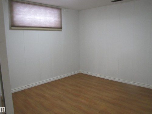 Room featuring wood-finish flooring, white panel walls, and a window with a cellular shade - 7135 87 Street, Edmonton, AB - Indoor Photo Showing Other Room