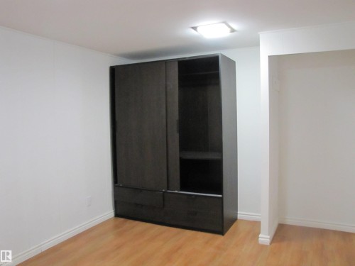 Built-in dark wood-finish wardrobe with sliding doors and integrated drawers - 7135 87 Street, Edmonton, AB - Indoor Photo Showing Other Room