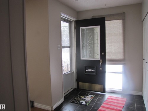 Entryway featuring a black door with leaded glass insert, dark tile flooring, and a sidelight with a privacy shade - 7135 87 Street, Edmonton, AB - Indoor Photo Showing Other Room